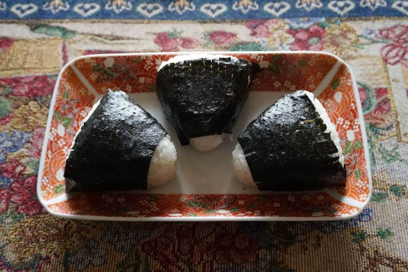 三角形饭团用海苔包裹,盛放在传统的日式盘子里