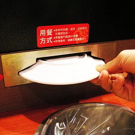 顾客从输送带上取下的带盖菜品